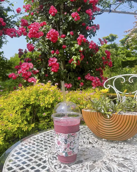 Bir bardak çay, bir çiçek ve masanın üzerinde bir buket çiçek.