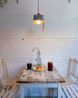 Beyaz lambalı bir masa ve tuğla duvarda bir fincan çay.