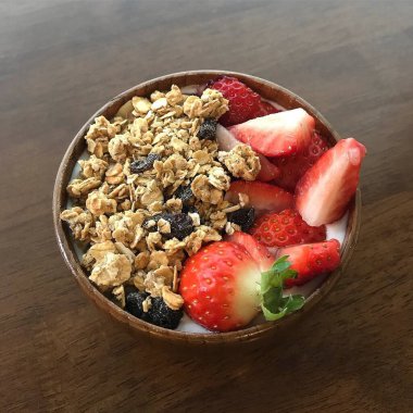 Sağlıklı kahvaltı. Çilekli taze müsli ve ahşap masada yabanmersini..
