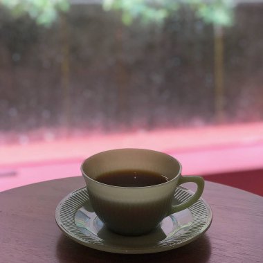 Kahve fincanı ve kahve çekirdekleri ahşap masada.