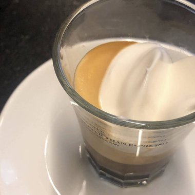 Kremalı bir fincan kahve ve bir bardak su.