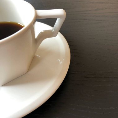 Siyah kahve fincanı beyaz ahşap masada.