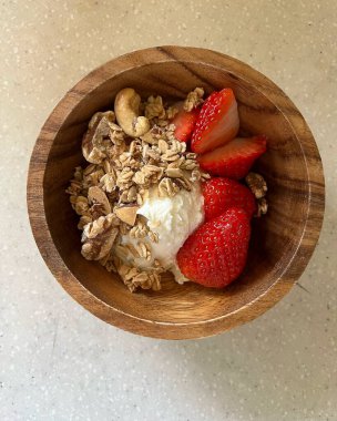 Tahta kaşıkla kasede taze çilek ve tahta arka planda kaşık.