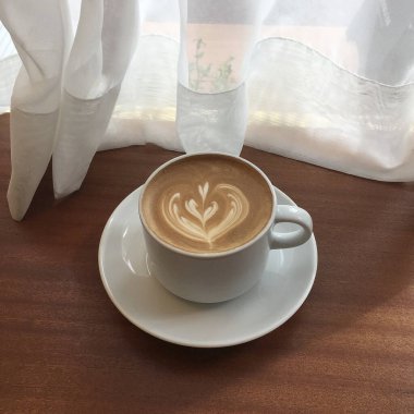 Masada beyaz köpüklü bir fincan sütlü kahve.