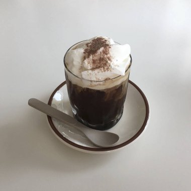 Bir fincan kapuçino, beyaz bir masada çikolata kremalı.