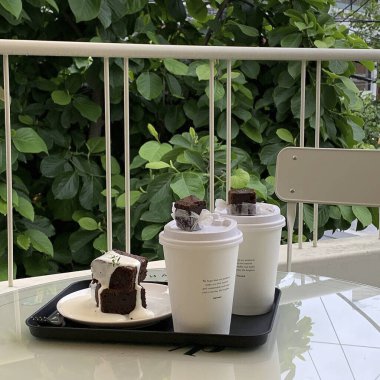 Beyaz bir fincan kahve ve ahşap bir masanın üzerinde beyaz bir pasta.