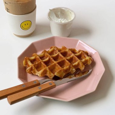 Sütlü bir waffle ve ahşap bir masada bir fincan çay.