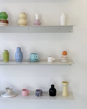 Mutfaktaki raflarda farklı seramik çanaklar bulunan seramik vazolar.