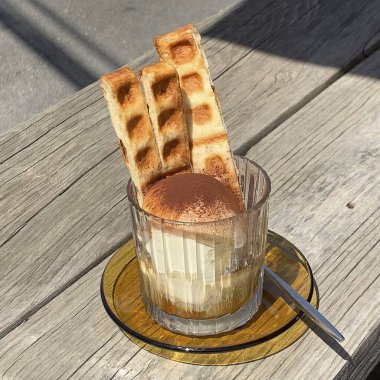 Lezzetli bir kahvenin dikey görüntüsü, cam bir bardakta, ahşap bir masada dondurmayla.