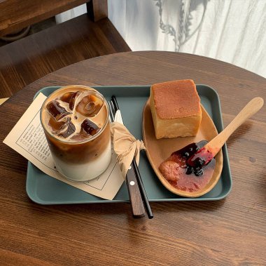 Bir fincan kahve ve ahşap masada bir pasta.