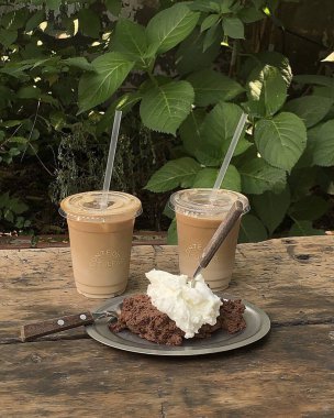 Beyaz kremalı bir bardak kahve ve ahşap bir masada iki beyaz bardak..