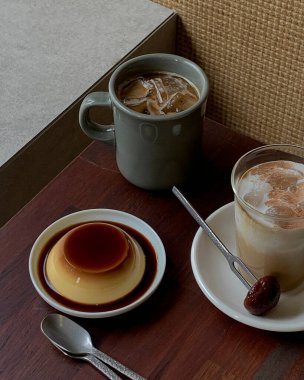 Tahta bir masanın üzerinde bir bardak sütle bir fincan kahve.