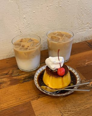 Bir fincan kahve, üzerinde pasta olan tahta bir masa.