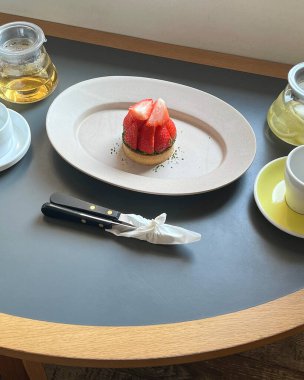 Bir fincan çay ve beyaz bir masada kek.