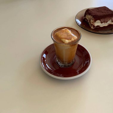 Bir fincan sıcak cappuccino kahve ve masaya bir parça kahve..