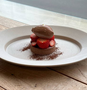 Çilekli çikolatalı pasta ve tabakta çikolata şurubu.