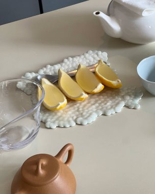 Bir fincan çay ve limonlu beyaz çaydanlık.