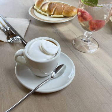 Restorandaki ahşap masada taze kruvasan ve kahve.