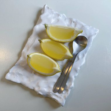 Tahtada beyaz bir tabakta limon dilimleri.