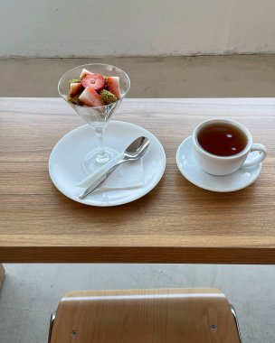 Bir fincan siyah çay kaşıklı çay ve tahta bir masada kaşıkla çay tabağı. Kahvaltı, dinlenme, rahatlama konsepti.