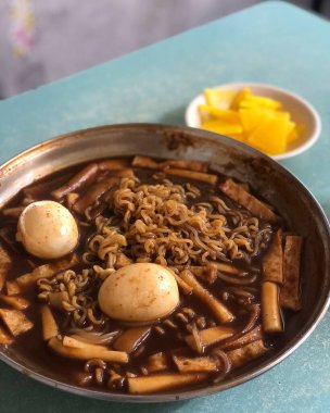 Siyah tabakta tavuk ve sebzeli erişte.