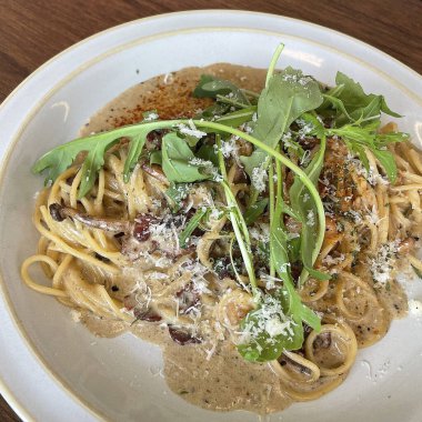 Beyaz tabakta et ve peynirli spagetti.