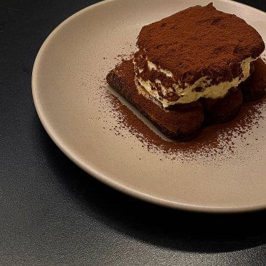 Tiramisu siyah plakalı ve siyah arkaplanlı. Tiramisu tatlısı. İtalyan tatlısı.