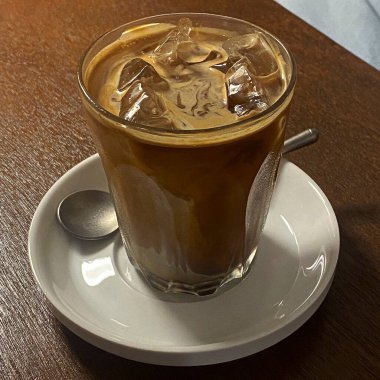 Tahta bir masada buzlu ve çikolatalı bir kahve fincanı.