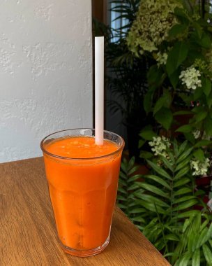 Masanın üzerinde bir bardak taze meyve suyu ve pipet var.