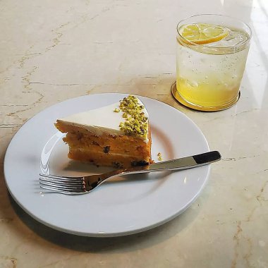 Bir bardak limonlu çay ve beyaz tabakta bir bardak su.