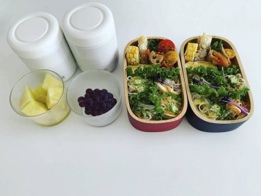 Plastik kabın içindeki sağlıklı yiyecekler ve beyaz arka planda taze salata.