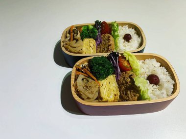 Tavuklu, sebzeli ve beyaz arkaplanlı bir kutu pirinç.