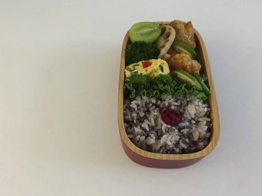 Japon suşisi pirinç ve sebzeli ahşap bir masada yuvarlanıyor.