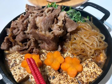 Siyah kasede domuz etli erişte ve sebze.