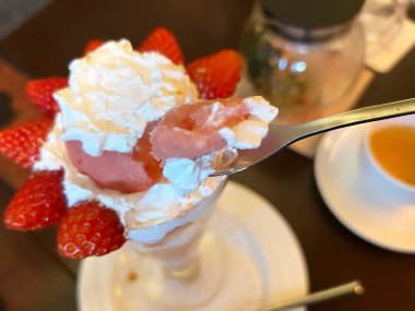 Cam bir fincanda kaşık ve kaşıkla çilek kreması.