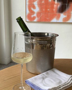 Masanın üzerinde bir kova şampanyayla bir şişe şarap.