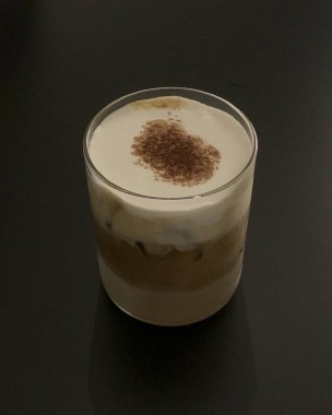 Siyah arka planda beyaz çikolatalı bir fincan kahve.