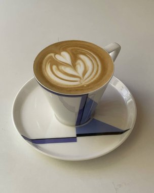 Bir fincan cappuccino kahve ve ahşap bir masada latte sanatı..