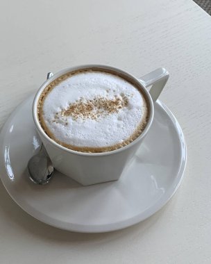 Sütlü bir fincan kahve ve masada bir fincan çay tabağı.