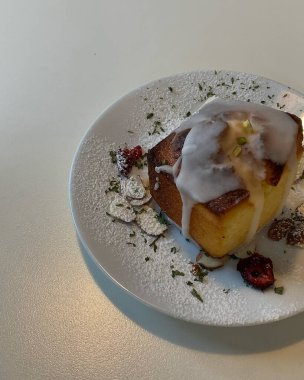 Kremalı ve beyaz tabakta beyaz bir tabak çikolatalı lezzetli bir pastanın dikey çekimi.