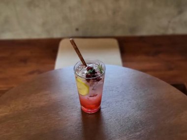 Ahşap zemin üzerinde kırmızı kokteyl olan cam.