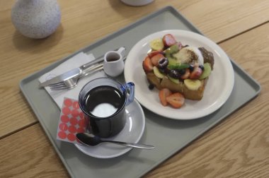 Kahvaltı, kahve, çay fincanı ve tost masada.