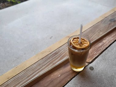 Sütlü buzlu kahve fincanı ve ahşap arka planda buz