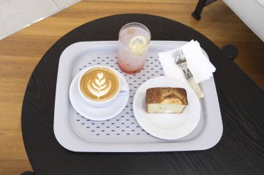 Bir fincan kahve ve ahşap masada bir kruvasan.