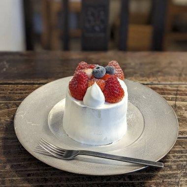 Bir restorandaki masada duran çilekli kekin dikey görüntüsü.