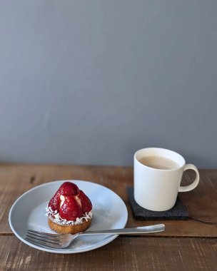 Kahveli beyaz tabakta çilekli kek.