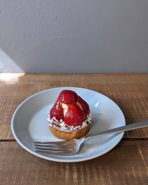 Masanın üzerinde çilek ve krema olan bir tabağın yakın plan fotoğrafı.
