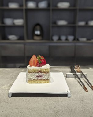 Beyaz bir masada bir bardak süt ve bir bardak sütle kek ve çilek..