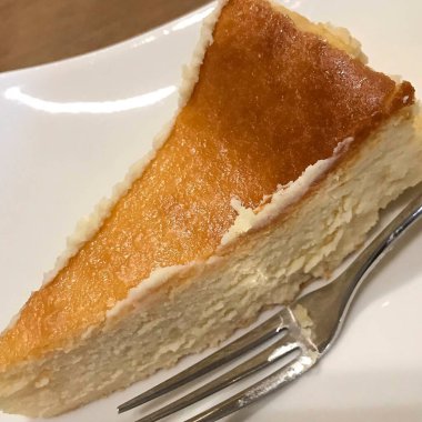 Masada beyaz tabakta bir dilim cheesecake.