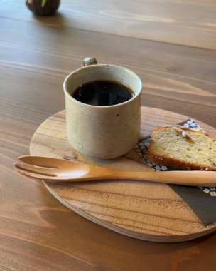 Tahta bir masada bir fincan kahve ve kek.